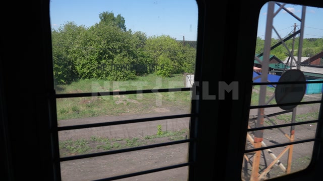 Вид из окна электрички, лето, день, в кадре одноэтажные постройки, сельские дома