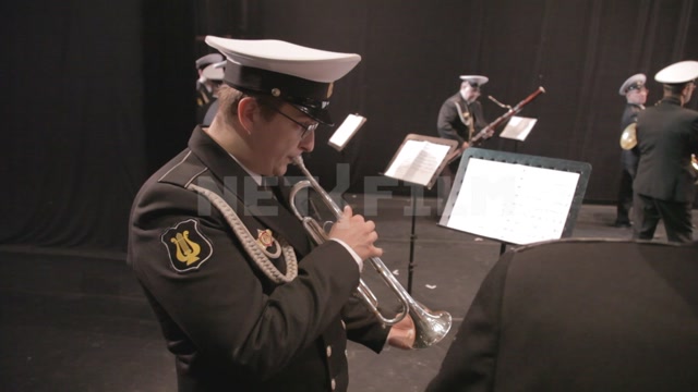 Military brass band members rehearse backstage