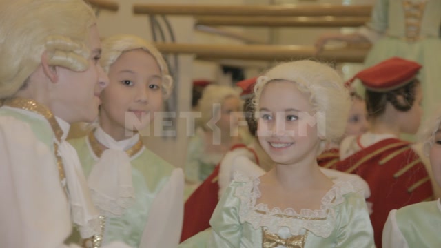 Children (students of the ballet school) in stage costumes and wigs before the start of the