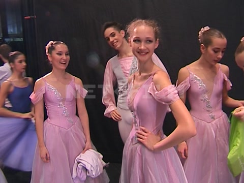 Young ballet dancers backstage, in stage costumes, preparing for a performance
