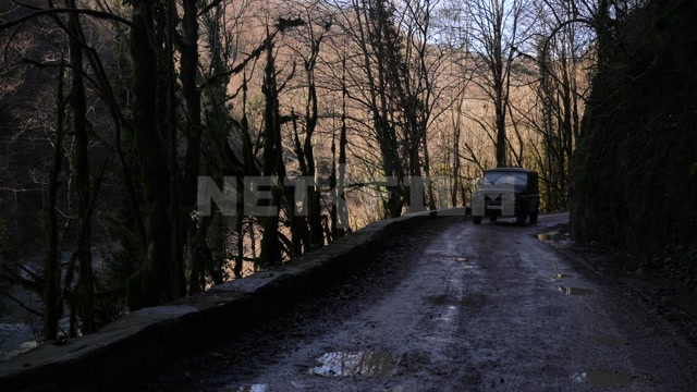 Абхазия, осень день. Горная дорога, проезжает УАЗ. Панорама на горы, утес